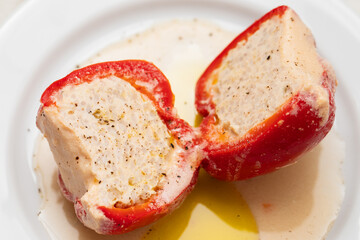Bell red peppers stuffed with meat, vegetables, cheese and herbs in baking dish on a ceramic background.