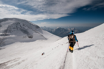 a girl walks along the snow-covered slope of Elbrus