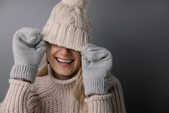cheerful smiling woman hiding face under knitted wool hat. trendy winter fashion clothing