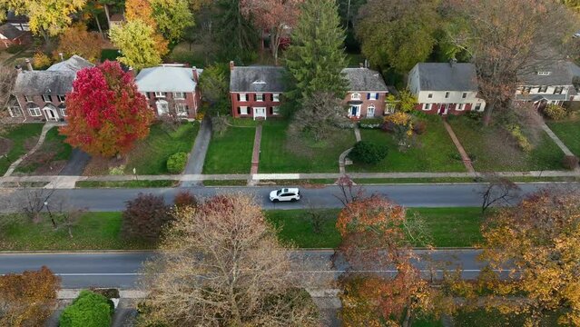 Aerial truck shot of SUV driving through suburban American town during autumn fall foliage.