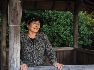 山の展望台にあるログハウスで景色を眺める高齢日本人女性