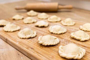 Fototapeta na wymiar Raw dumplings polish traditional perogies lying on wooden board in kitchen