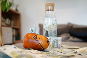 Saving five euro notes in a piggyband and a glass bottle 