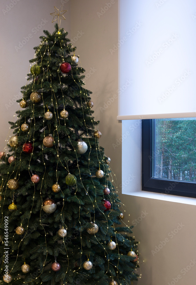 Poster roller blinds close up on the window near new year tree. white color roller shade on the antracite w