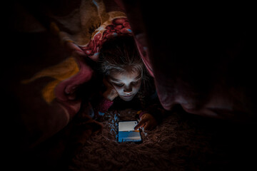 A girl with a mobile phone on the bed.