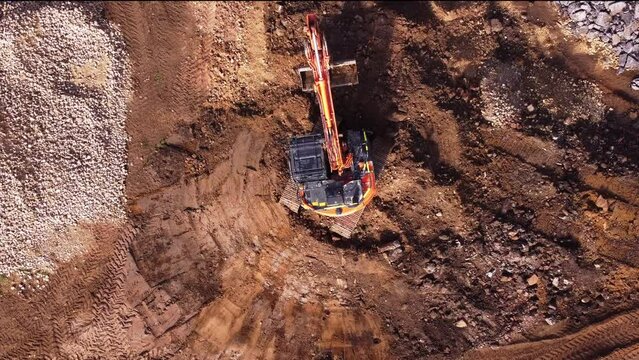 Excavator filling bucket with semi-dry concrete on construction site Aerial shot	