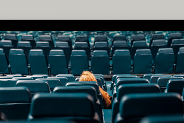 Abstract girl, lonely spectator in an empty cinema hall, empty seats
