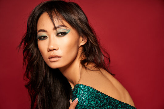 Vogue style close-up portrait of beautiful asian woman over red studio background