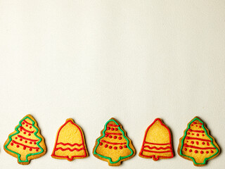 Christmas border of homemade colorful gingerbread cookies in shape of christmes tree and bell on...