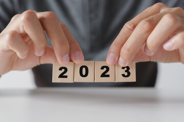 Man hand holding wooden cube block with 2023 year text . start to year 2023. happy new years...