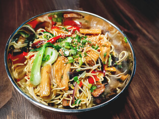 Bowl with noodles and stir fried vegetables. Bowl with food on wooden table.