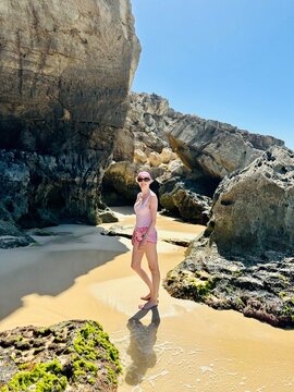 Femme devant des rochers en bord de plage