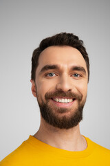 portrait of happy bearded man smiling at camera isolated on grey.