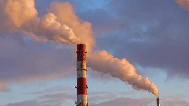 Toxic smoke clouds coming out of factory chimney at sunset. Air pollution and global warming caused by old industrial power plant