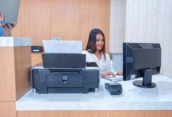 At hospital hall cashier sit at information counter near receipt printer check patient expense pay