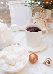  Winter, Christmas, New Year decoration composition, concept, background. White Mug, cup of hot tea, coffee, meringue, knitted plaid. Christmas lights. Christmas mood morning. Xmas greeting card.