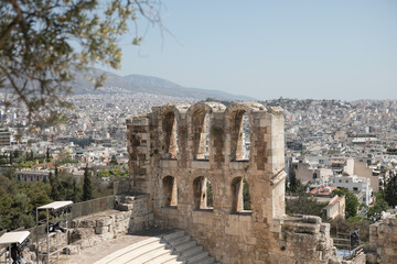 Fototapeta na wymiar Ancient Greek ruins in Athens, Greece, Europe. Odeon of Herodes Atticus overlooking city. This stone theater is famous landmark of Athens. Old monument close-up, remains of classical Athens.