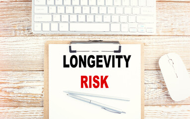 LONGEVITY RISK text on a clipboard with keyboard on wooden background