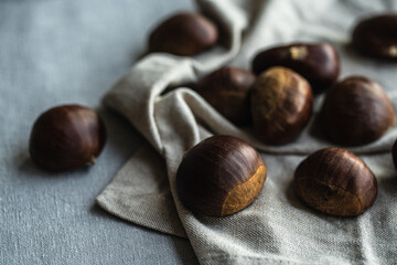 Step by step process of making roasted chestnuts. Heap of raw chestnuts on linen cloth.