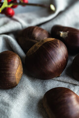 Step by step process of making roasted chestnuts. Heap of raw chestnuts on linen cloth.