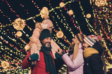 Portrait of attractive cheerful family having fun visiting festal eve fair shopping sale strolling traveling city urban outdoors