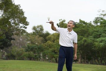 happy senior man playing badminton outdoor,  elderly people health care concept