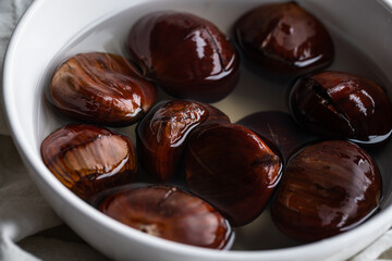 Step by step process of making roasted chestnuts. Chestnuts soaked in water before baking.