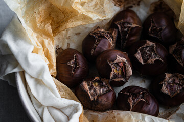 Step by step process of making roasted chestnuts. Oven baked chestnuts resting in wet towel before being peeled.