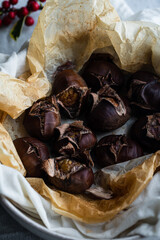 Step by step process of making roasted chestnuts. Oven baked chestnuts resting in wet towel before being peeled.