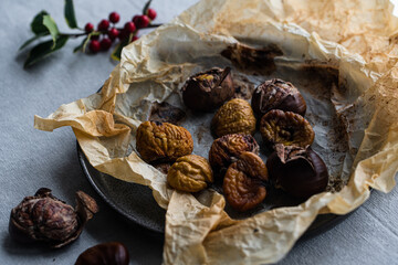 Step by step process of making roasted chestnuts. Peeled roasted chestnuts on baking paper on plate.