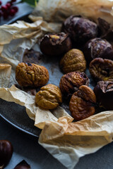 Step by step process of making roasted chestnuts. Peeled roasted chestnuts on baking paper on plate.