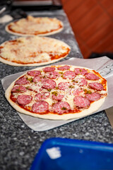 chef baker making pizza at kitchen. Put on landing shovel and send it to the oven.