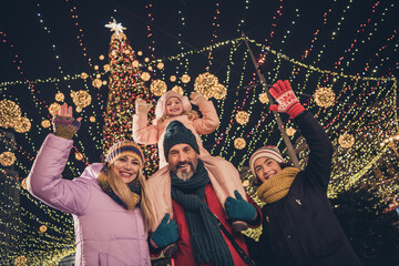 Photo of cheerful school children husband wife cuddling walking x-mas park waving arms riding shoulders urban city market