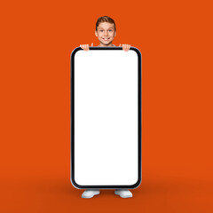 Fototapeta na wymiar Mobile Mockup. Cheerful Teen Boy Standing Behind Huge Blank Smartphone