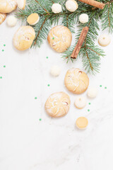 Fototapeta na wymiar candies and cookies with christmas tree branches on white marble background
