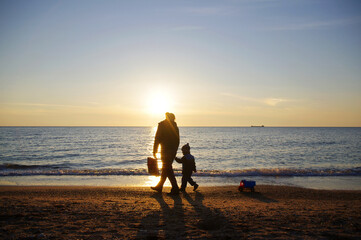 a woman with her son walk on the beach.