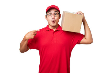 Friendly asian courier wearing red shirt and cap holding box on shoulder and pointing at package - obrazy, fototapety, plakaty