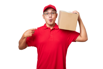 Friendly asian courier wearing red shirt and cap holding box on shoulder and pointing at package