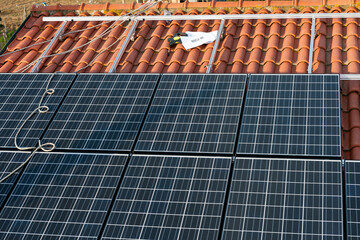 Solar panels are mounted half way on an aluminum structure on a red Italian tile roof