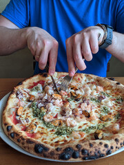 Young person, man holding pizza with seafood close up at restaurant.