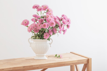 pink chrysanthemums in white vase on white interior