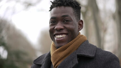 Charismatic happy black African young man smiling outside wearing scarf and winter coat