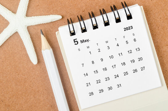 The May 2023 Monthly calendar with Starfish and pencil on wooden background.
