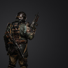 Back view shot of post apocalyptic stalker holding shotgun against grey background.