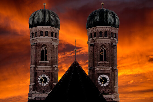 Die Silhouette der beiden Kirchtürme der Frauenkirche in München vor dramatischem Dämmerungshimmel