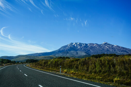 road to mountain and blue sky in background in summer and autumn at tongariro national park, taupo, new zealand, wide screen and curve street on left frame 