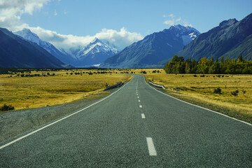 Naklejka premium road to mount cook, new zealand with summer and autumn surround, straight way and line of street in clearly day