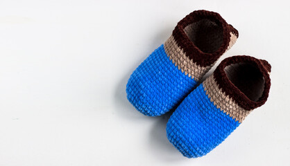 Knitted slippers in blue and brown colors. Plush yarn slippers on a white background