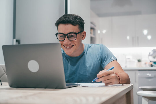 One Young Teenager Studying And Working At Home At Night On The Table Using Laptop Pc Smiling And Having Fun Doing Homework.