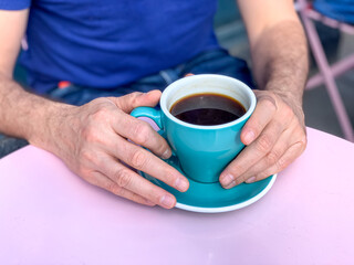 Man is drinking americano coffee. Mans hands holding coffee mug.Morning coffee in tiffany color...